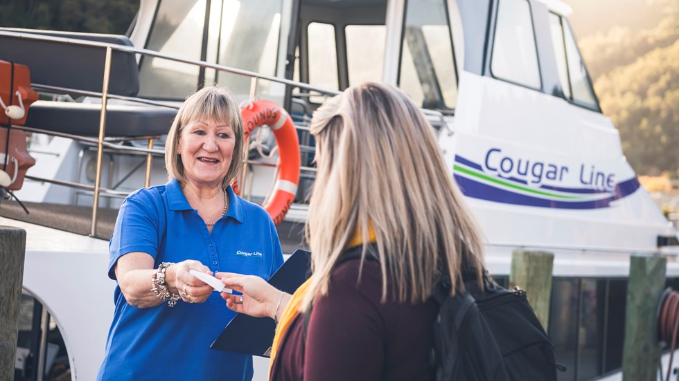 A passenger is greeted by a smiling Cougar Line staff member while boarding in Picton in the Marlborough Sounds, New Zealand.