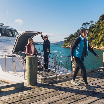 Two walkers disembarking from the Cougar Line boat at Ship Cove/Meretoto ready to walk on the Queen Charlotte Track.