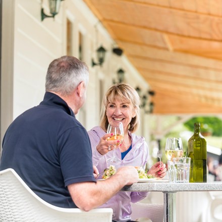 A couple dines at a table on the verandah at Furneaux Lodge in the Marlborough Sounds, New Zealand.