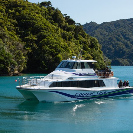 A Cougar Line boat with passengers onboard cruises into a calm bay in the Queen Charlotte Sound/Tōtaranui, Marlborough Sounds, New Zealand.