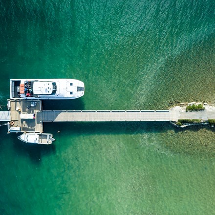 An aerial view of the Furneaux Lodge jetty, boat shed, Cougar Line boat and smaller boats in the Marlborough Sounds, New Zealand.